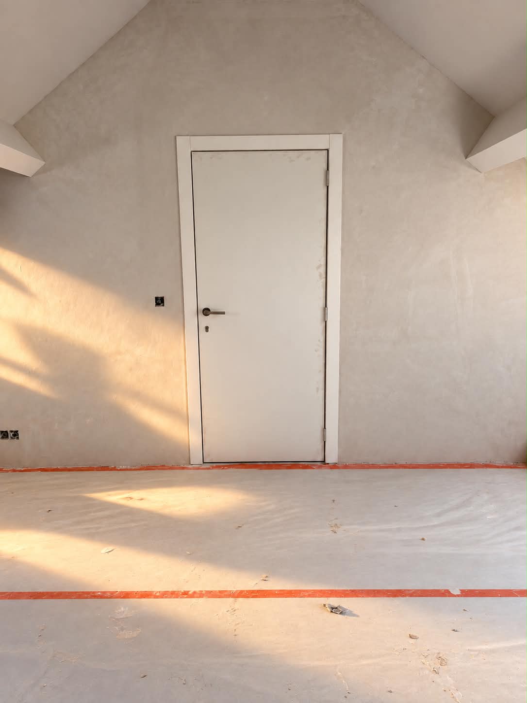 Mur enduit et porte intérieure sous les rampants