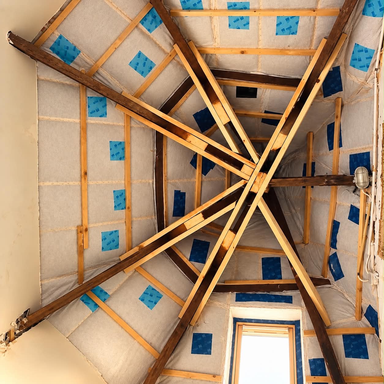 Membrane et tasseaux en bois autour de la charpente croisée avant habillage